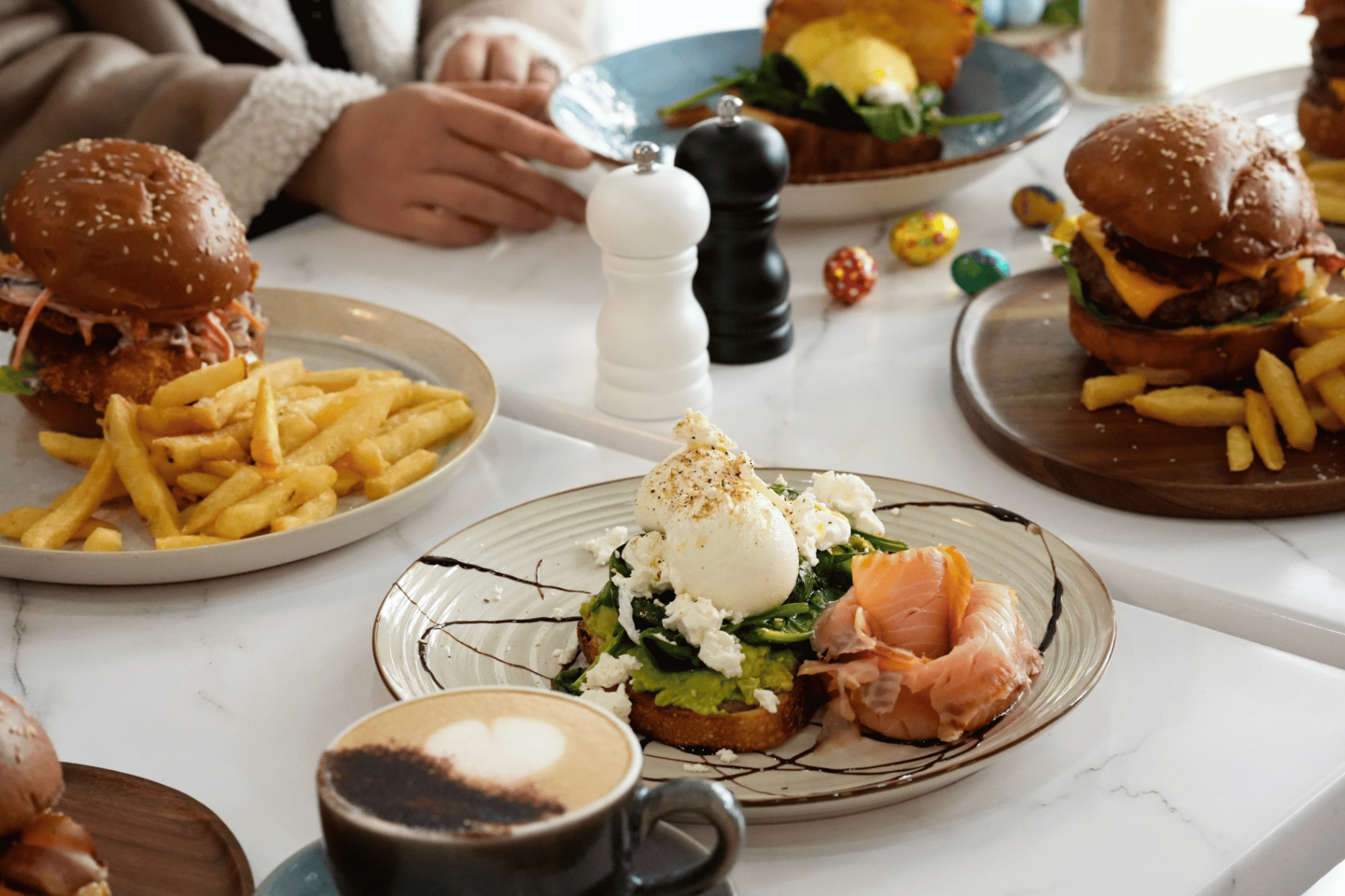 Orchid Cafe table spread with burgers, eggs benedict, smashed avo and coffee